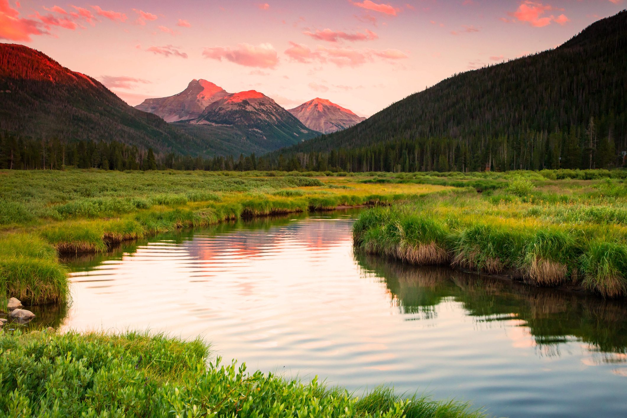 Bear River flowing through grasslands with mountains in the background at sunset.