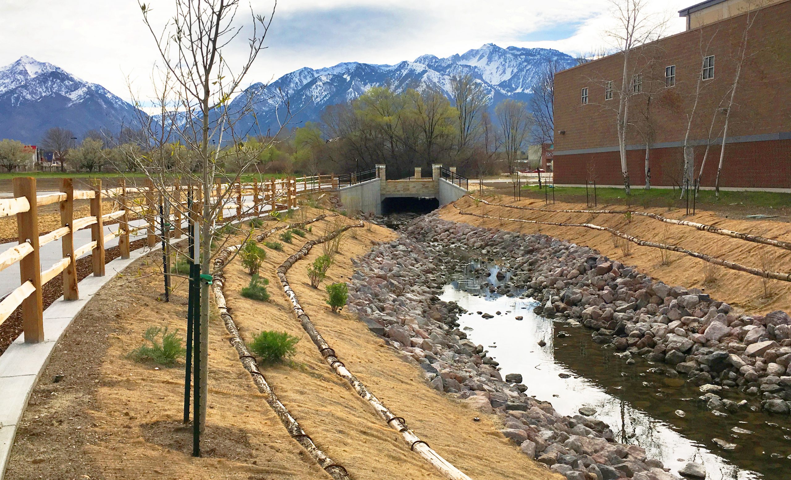 Dry Creek channel with mountains in the background and brick building beside it.