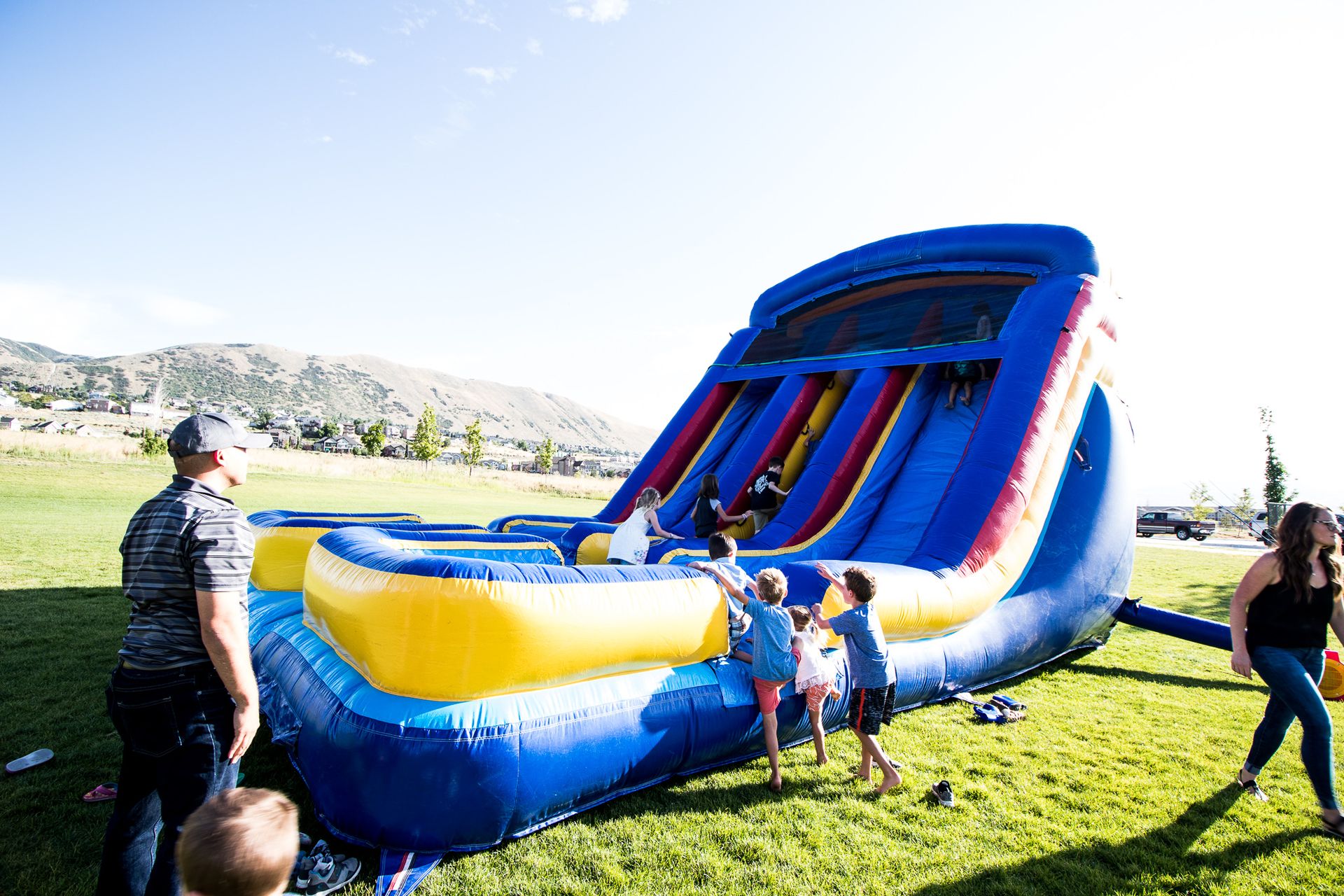 Kids playing in blow up bouncy house in grass field.