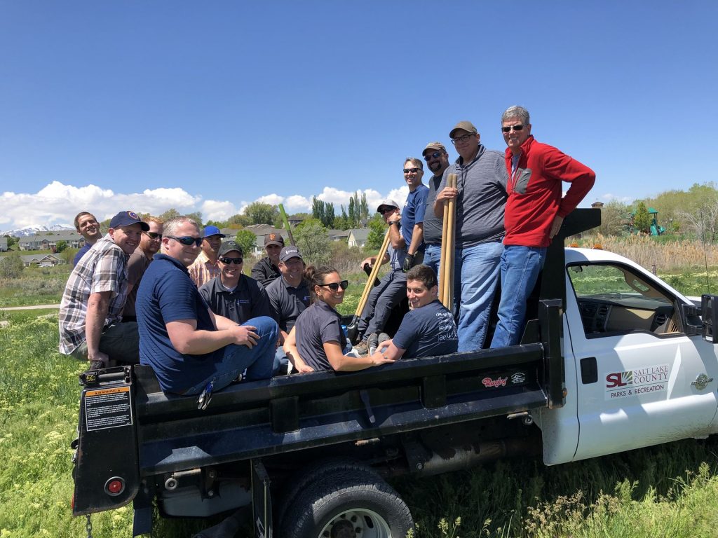 Group of men and a woman sitting and smiling in truck bed.